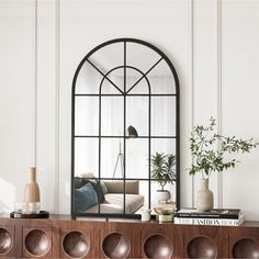 a living room with an arched window, books and vases on the shelf next to it