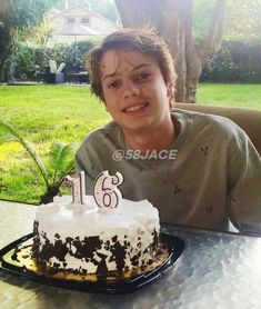 a boy sitting at a table with a cake in front of him