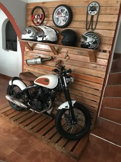 a motorcycle is parked in front of a wooden shelf with helmet racks on the wall