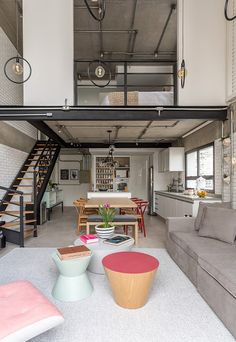 a living room filled with furniture and lots of windows next to a stair case that leads up to the second floor