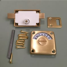 brass plated hardware and screws are laid out on a gray surface, including a door lock