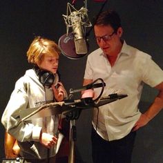 a man standing next to a little boy in front of a microphone and headphones