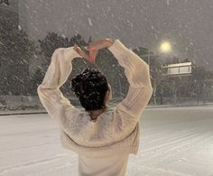 a woman standing in the snow holding her hands up