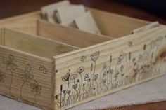 a wooden box with flowers drawn on the side sitting on top of a white cloth