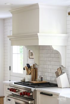 a stove top oven sitting inside of a kitchen next to a counter with utensils on it