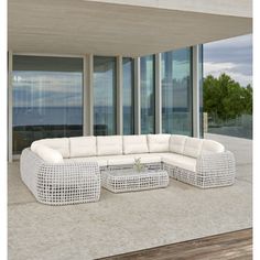 a large white couch sitting on top of a wooden floor next to tall glass windows