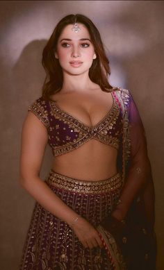 a woman in a purple lehenga posing for the camera with her hands on her hips