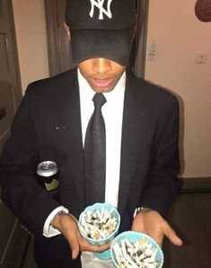 a man wearing a yankees hat holding two bowls of food