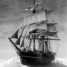 an old sailing ship in the middle of the ocean with snow on the ground behind it