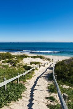 stairs lead down to the beach with blue water in the background and sand dunes on either side