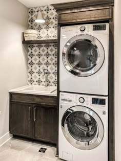 a washer and dryer in a small room with tile on the wall behind them