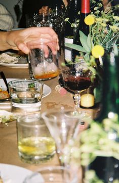 people are sitting at a table with wine glasses and flowers in vases on it