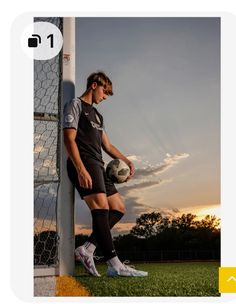 a young man holding a soccer ball next to a goalie post with the sun setting in the background