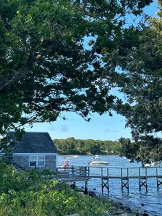 there is a small house on the side of the water with boats in the background