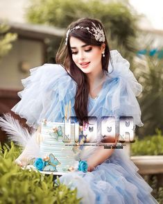 a woman in a blue dress holding a cake