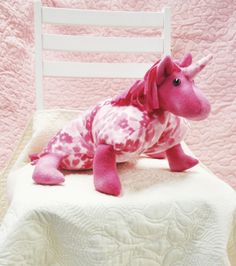 a pink stuffed animal laying on top of a white chair next to a pink quilt