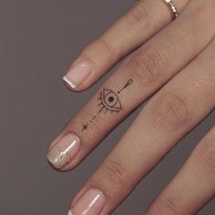 a woman's hand with a small tattoo on the middle finger and an eye