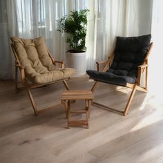 two chairs and a foot stool in front of a curtained window with a potted plant