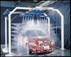 a car is being sprayed with water from a sprayer machine in a garage area