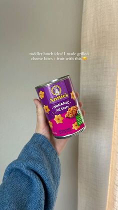 a person holding a can of food in front of a curtain with the words, stella's organics on it