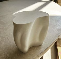 a white vase sitting on top of a table next to a window with sunlight streaming through it