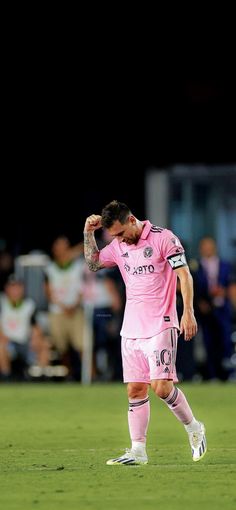 a soccer player is standing on the field with his hands behind his head and looking down