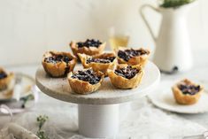 small tarts on a cake plate with flowers in the background