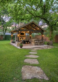 a gazebo in the middle of a yard with grass and stepping stones leading up to it