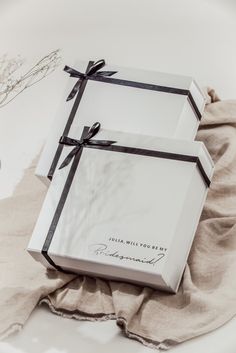 two wrapped gift boxes sitting on top of a white cloth covered table next to each other