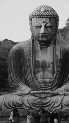 black and white photograph of people standing in front of a large buddha statue