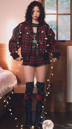 a woman is dressed in plaid clothes and boots with lights on the floor behind her