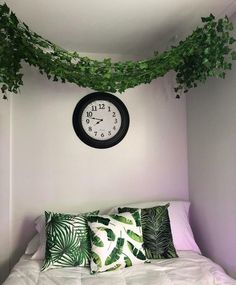 a clock hanging from the ceiling above a bed with pillows and blankets on top of it