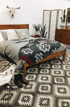 a bed room with a neatly made bed next to a dresser and two planters