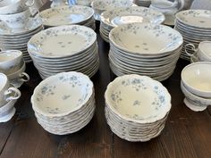 a table topped with lots of white and blue dishes on top of a wooden table