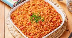 a large dish of rice and vegetables on a wooden table with water glasses, napkins and utensils