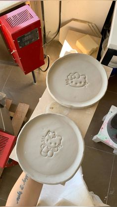 two white plates sitting on top of a counter next to a red machine and paper towel