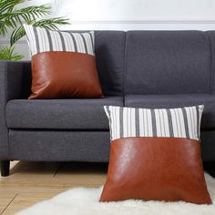 two brown and white pillows sitting on top of a gray couch next to a potted plant