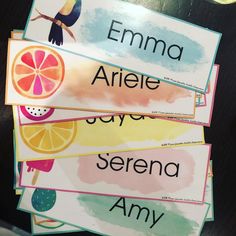 four different types of name tags on a table with an apple and orange in the background