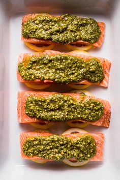 salmon with pesto on top and tomatoes in the middle, sitting on a white tray