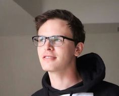 a young man wearing glasses and a black hoodie