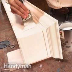 a person painting a cabinet with white paint