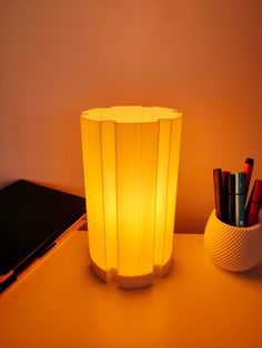 a lamp that is on top of a table next to a pen holder and notebook