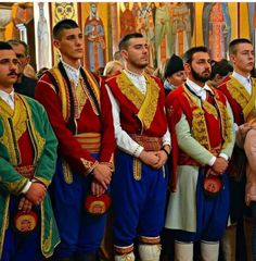 the men are dressed in traditional russian garb and standing next to each other with their hands together