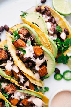 three tacos with black beans, avocado and cilantro on a plate