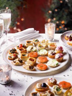 an assortment of appetizers are displayed on a table with wine glasses and candles