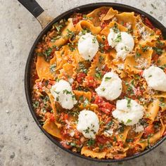 a skillet filled with pasta and cheese topped with parmesan on the side