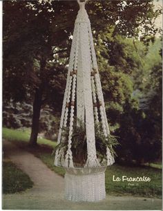 a white crocheted plant hanger in the shape of a tree with plants growing out of it