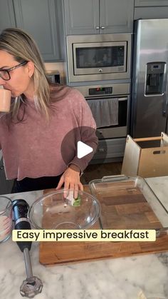 a woman standing in front of a kitchen counter with an empty bowl on top of it