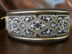 a black and white dog collar with gold trimmings on a brown leather couch