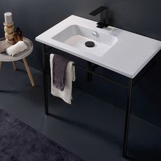 a white sink sitting on top of a bathroom counter next to a stool and towel rack